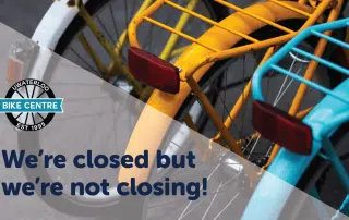 Image of the rear racks and reflectors of various colored bicycles with text overlay: "We're closed for now but not closing! Waterloo Bike Centre Est. 1999, see you after our Fall Closure.