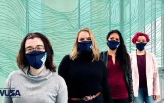 Four individuals wearing blue masks stand in a line with a teal wavy-patterned backdrop, ready for the Term Wrap-up. A WUSA logo is visible in the bottom left corner.