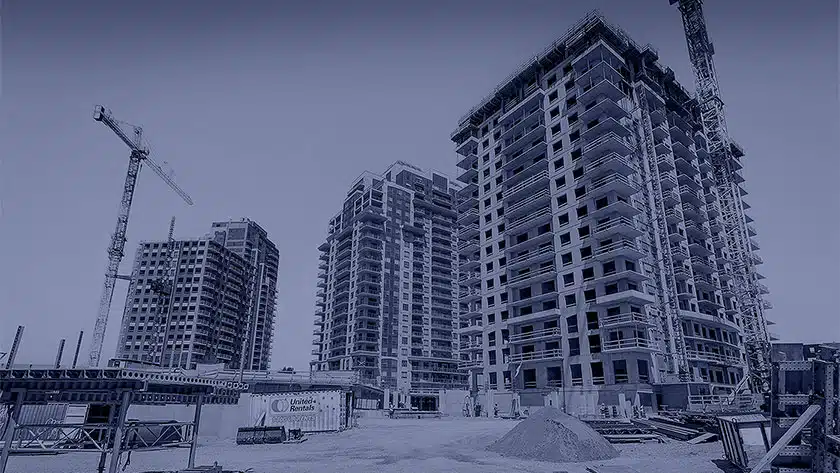 A construction site with multiple high-rise buildings in progress, surrounded by cranes and construction equipment.