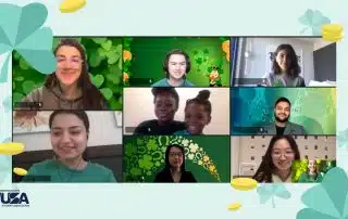 A group of people in a virtual meeting, with some dressed in green and various themed backgrounds to celebrate St. Patrick's Day. The Waterloo Undergraduate Student Association (WUSA) logo is in the bottom left corner.