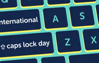 A keyboard with keys labeled "International Caps Lock Day," "caps lock day," and letters A, S, and Z on a green background.