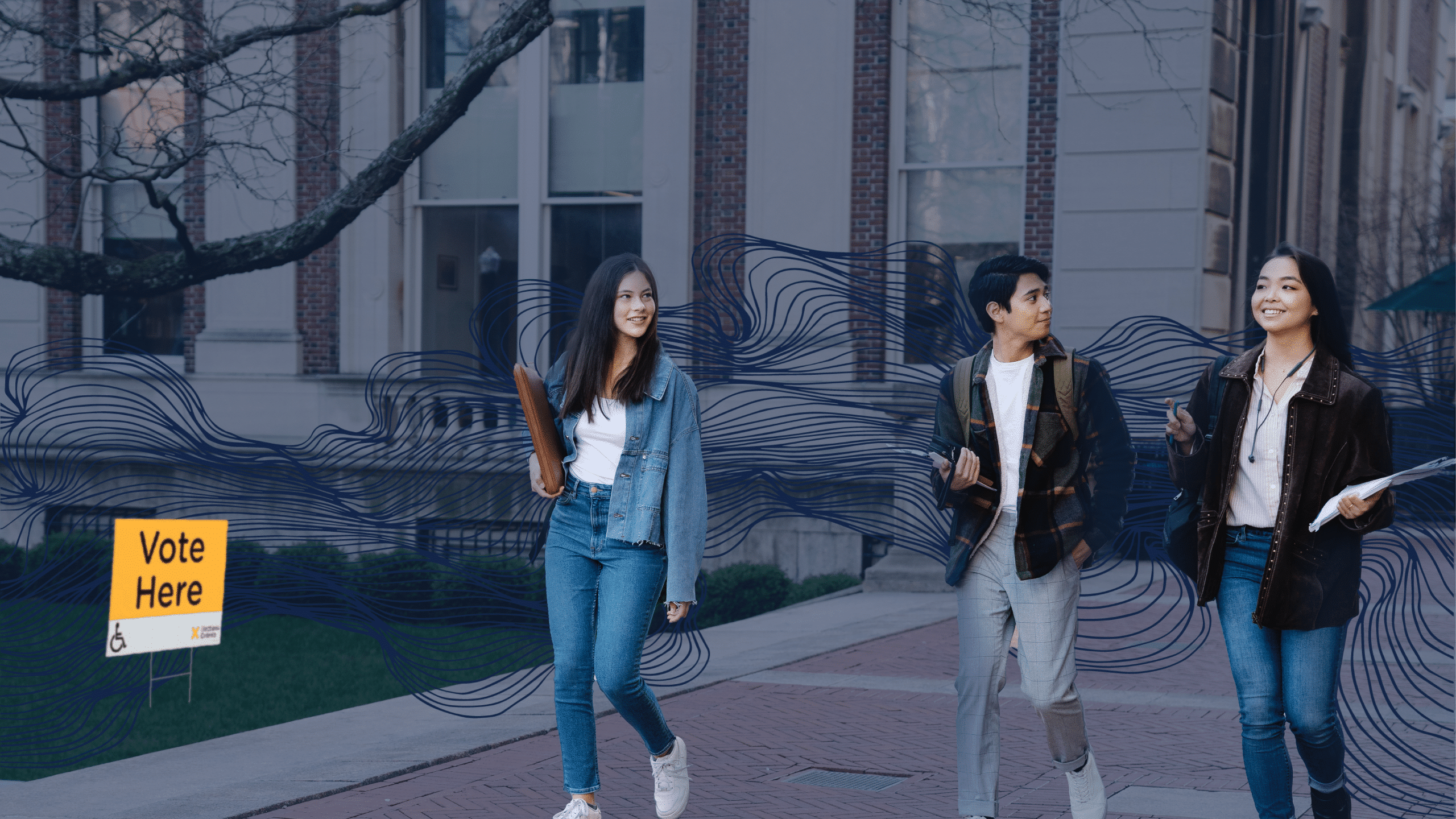 Three students walk together on a stone-paved pathway near a building with columns and large windows. All wear casual clothing and carry items like a book, a backpack, and papers. A yellow “Vote Here” sign with wheelchair accessibility symbol stands on the grassy area, urging participation in the Ontario Provincial Election in June 2022. Three young people walk on a campus sidewalk, passing by a "Vote Here" sign with an arrow. They carry books and appear to be engaged in conversation about the Ontario Provincial Election taking place in June 2022.
