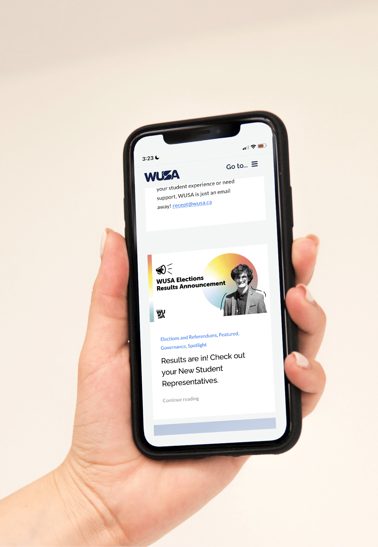 A hand holding a smartphone displaying an announcement from WUSA. The screen shows a notification about WUSA Elections Results. The announcement includes an image of a person and a message about checking out the new student representatives.