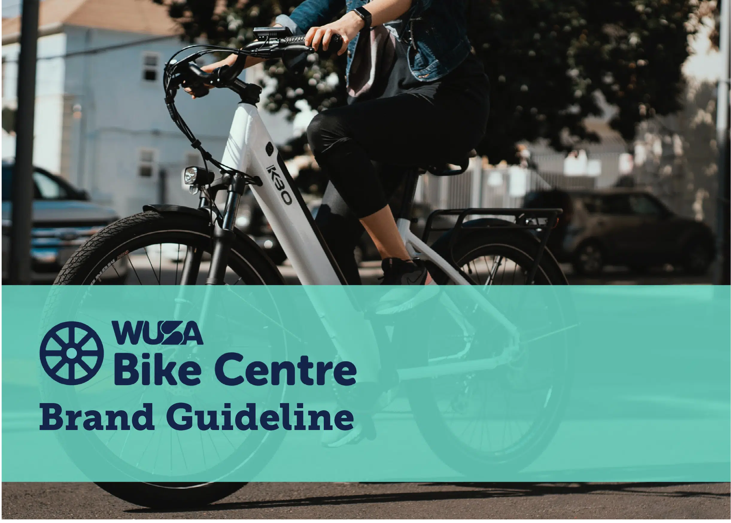 A person rides a white bicycle on a street with buildings and parked cars in the background. The image has a teal rectangle overlay with the text "WUSA Bike Centre Brand Guideline" and a wheel icon on the left side.