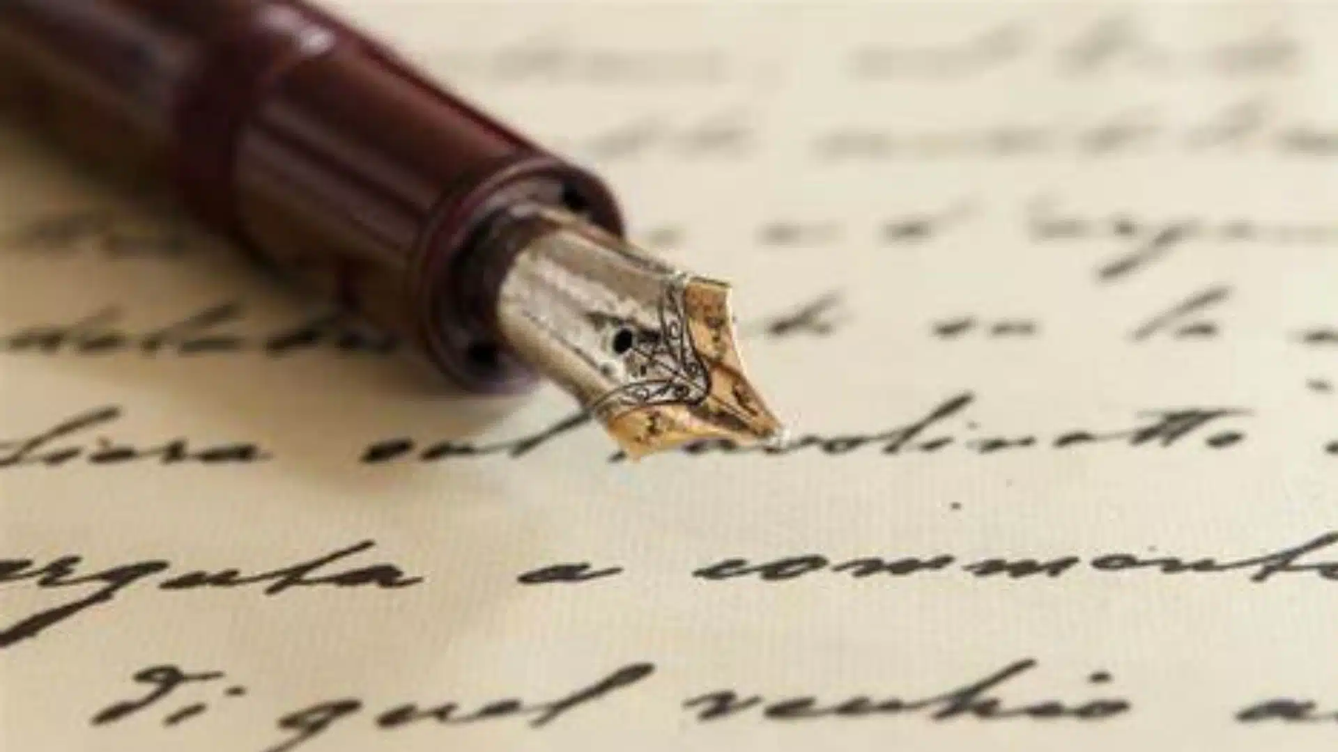 A close-up image of a vintage fountain pen with a metal nib resting on a piece of handwritten verse. The handwritten text is blurred, making it unreadable, while the details of the pen and its nib are in sharp focus.