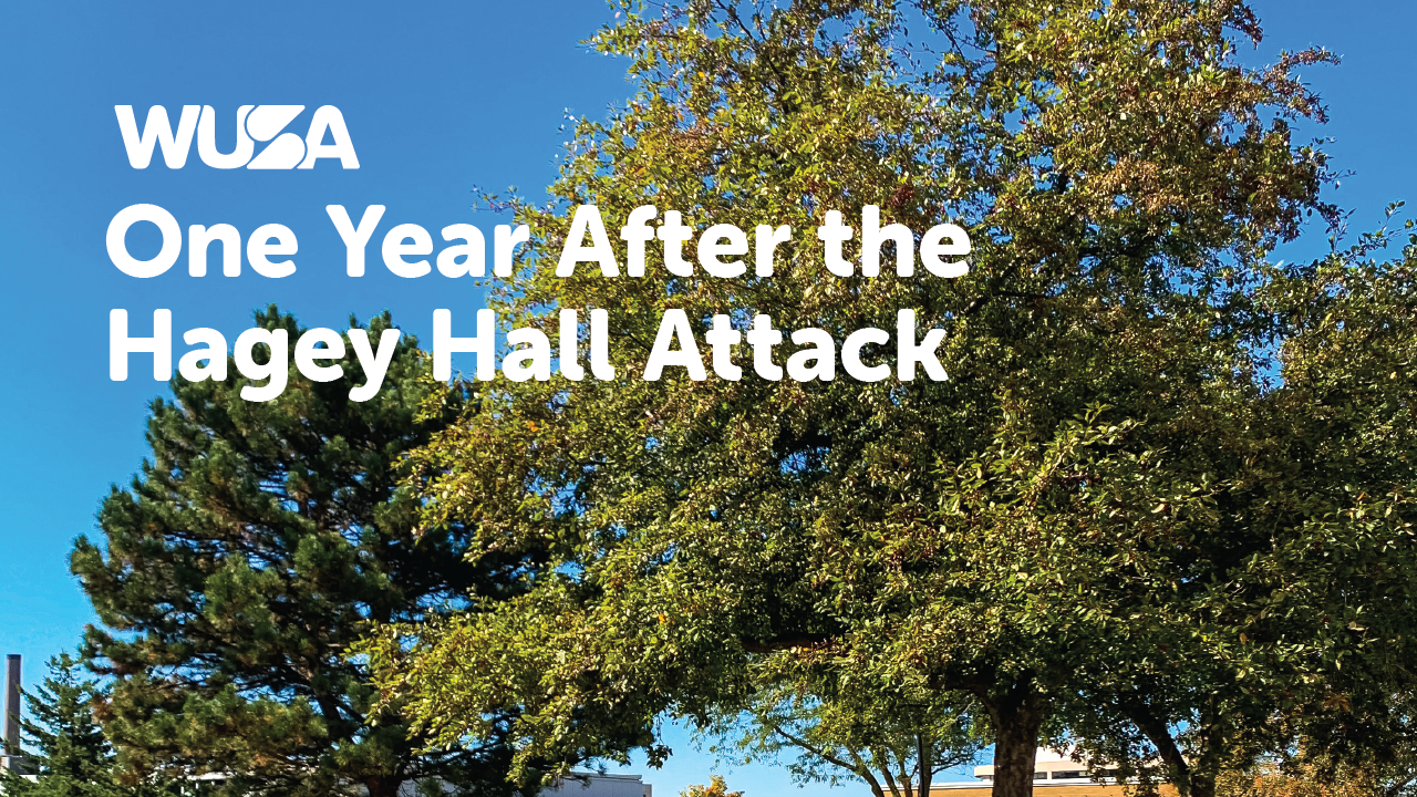 WUSA text overlaid on an image of an outdoor scene with trees and a clear blue sky, accompanied by the words "One Year After the Hagey Hall Attack.