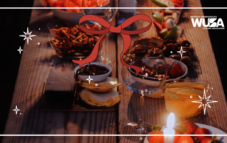 Festive table with snacks, candles, and drinks, adorned with a ribbon graphic on a dark wooden surface.