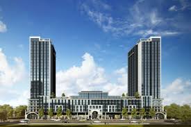 Modern building complex with two tall towers and a central section, designed for on-campus student housing, set against a blue sky with clouds.