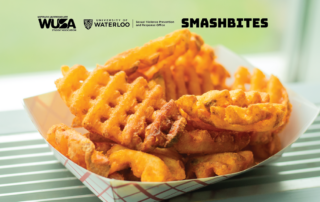 A basket of crispy waffle fries sits on the counter, perfectly seasoned. In the background, logos for WUSA, University of Waterloo, and Smashbites subtly remind you of where to get these delightful F.R.I.E.S.