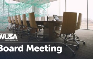 The boardroom sits ready for the WUSA Student Association, featuring a long table and swivel chairs bathed in natural light streaming through large windows, setting the perfect stage for a productive board meeting.