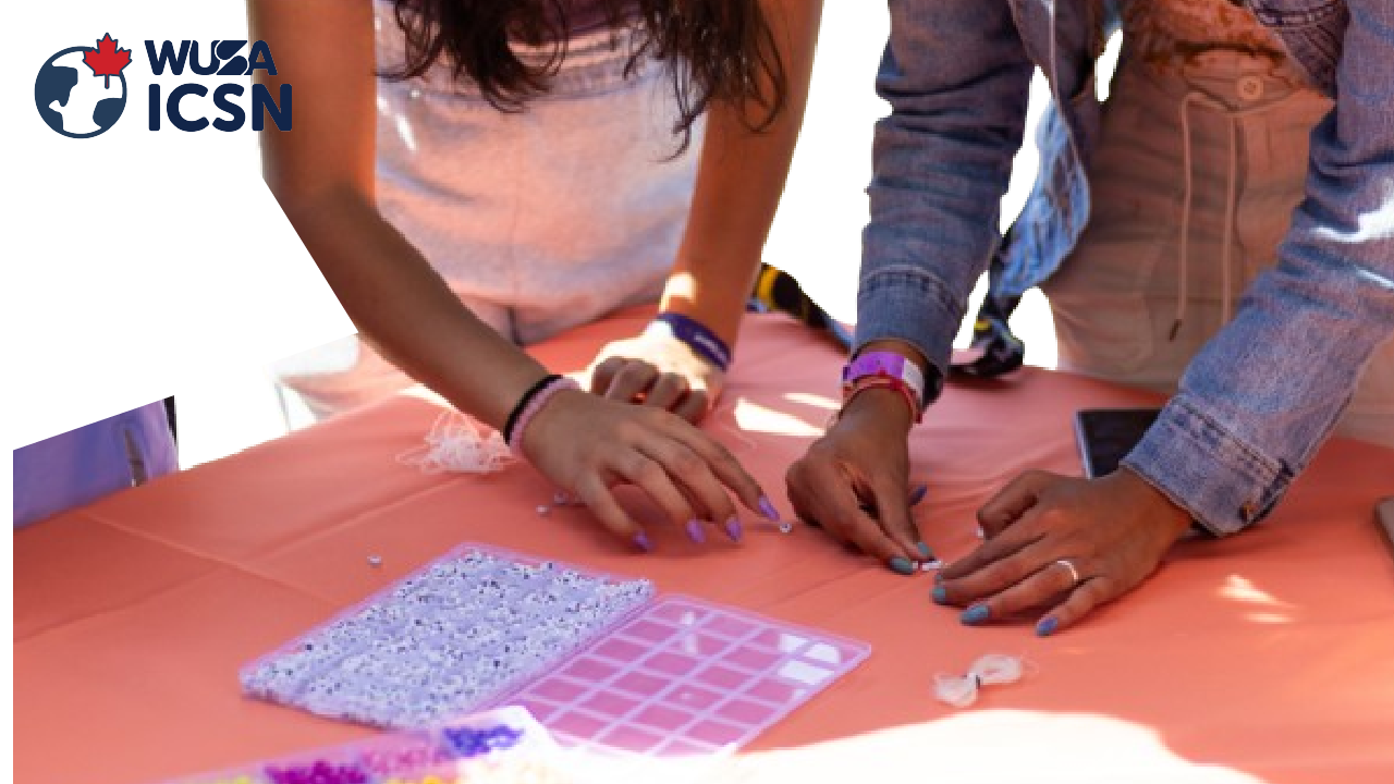 People enjoy a Stress-Free Friday, crafting with beads at a table covered with an orange cloth under the "WUSA ICSN" logo.