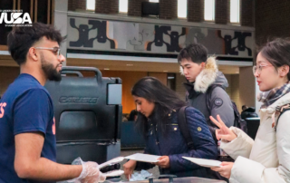 Students, clad in winter clothing, gathered at the counter for a warm welcome brunch during the campus event.