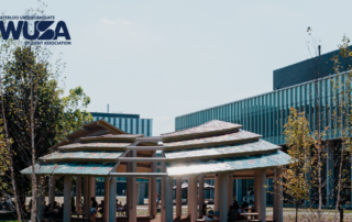 A modern pavilion with tiered roofs stands proudly on a university campus, harmoniously integrating Indigenous voices into its design, surrounded by trees and contemporary buildings.