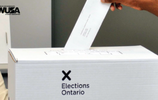 A person casts their vote into an Elections Ontario box, preparing for the upcoming provincial election.