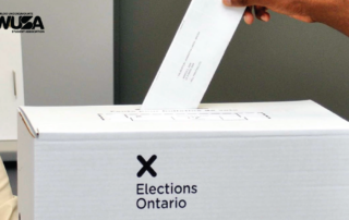 A hand places a ballot into an Elections Ontario box, shaping the future of the provincial election and its candidates.