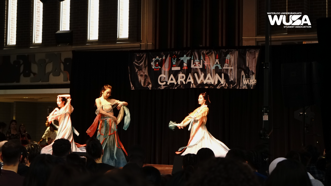 Three dancers in traditional attire gracefully perform on stage, embodying the vibrant essence of the Cultural Caravan event.