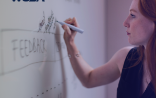 A person writes on a whiteboard with the word "FEEDBACK" prominently displayed, alongside a logo in the corner. This moment captures the essence of provincial advocacy, emphasizing WUSA's commitment to advocating for change.