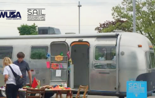 A silver trailer with an open door serves as a Pop-Up Art Lab, featuring art supplies and people nearby; SAIL and WUSA logos are visible.