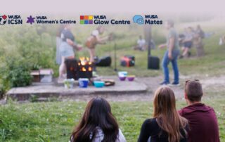 Three people sit on grass watching a group gather around a campfire, celebrating Bonfire Night; four WUSA centre logos appear above.
