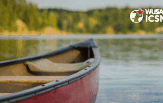 A red canoe rests on a calm lake beneath the WUSA ICSN logo in the top right corner, capturing the spirit of Canoe the Grand.