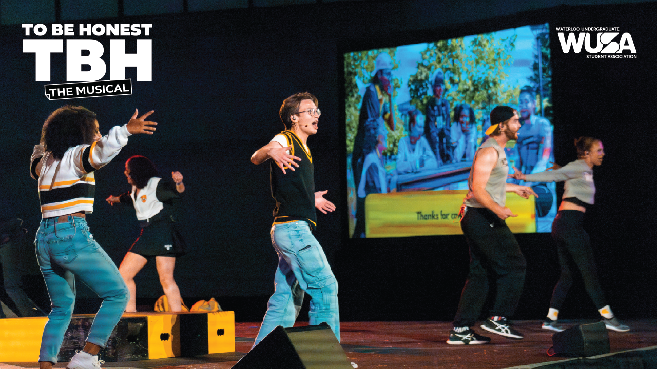 Four performers dance energetically on stage as the screen behind them displays "To Be Honest: The Musical," capturing the vibrant spirit of this captivating musical performance.