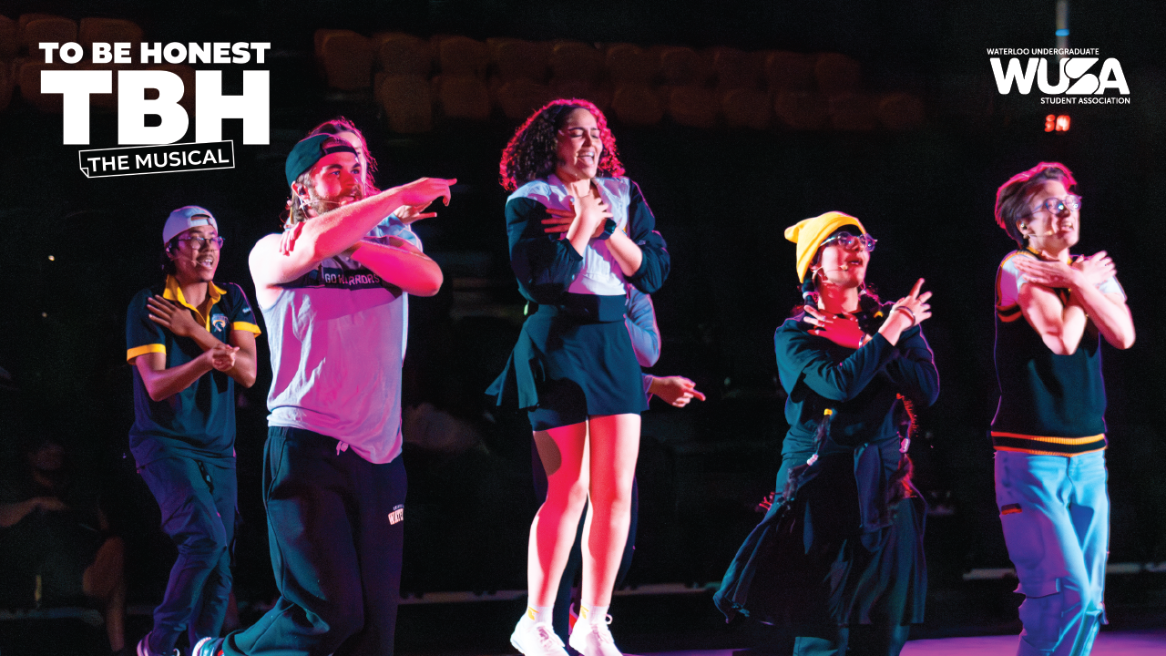 Five performers energetically dancing on stage under colorful lights; "To Be Honest: The Musical" text is displayed.