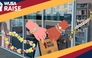 Two hands wearing friendship bracelets with "WUSA RAISE" and colorful beads, in front of an office display—perfect for celebrating Friendship Bracelet Night or inspiring your next bracelet making session.