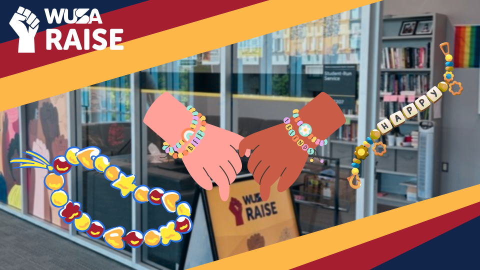 Two hands wearing friendship bracelets with "WUSA RAISE" and colorful beads, in front of an office display—perfect for celebrating Friendship Bracelet Night or inspiring your next bracelet making session.