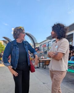 WUSA President Damian Mikhail, wearing a brown shirt and brown pants, talking to Mayor Dorothy McCabe who is wearing a black shirt, black pants, and a denim jacket.