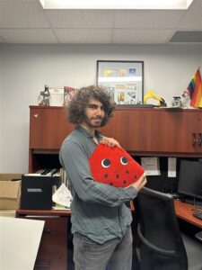 WUSA President Damian Mikhail holding a watermelon stuffie.