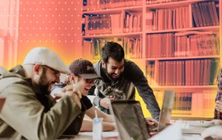 Four people laughing and working together at laptops in a colorful, modern library or office space, planning for Fall 2025 and chatting excitedly about the upcoming WAGS Hockey Night.