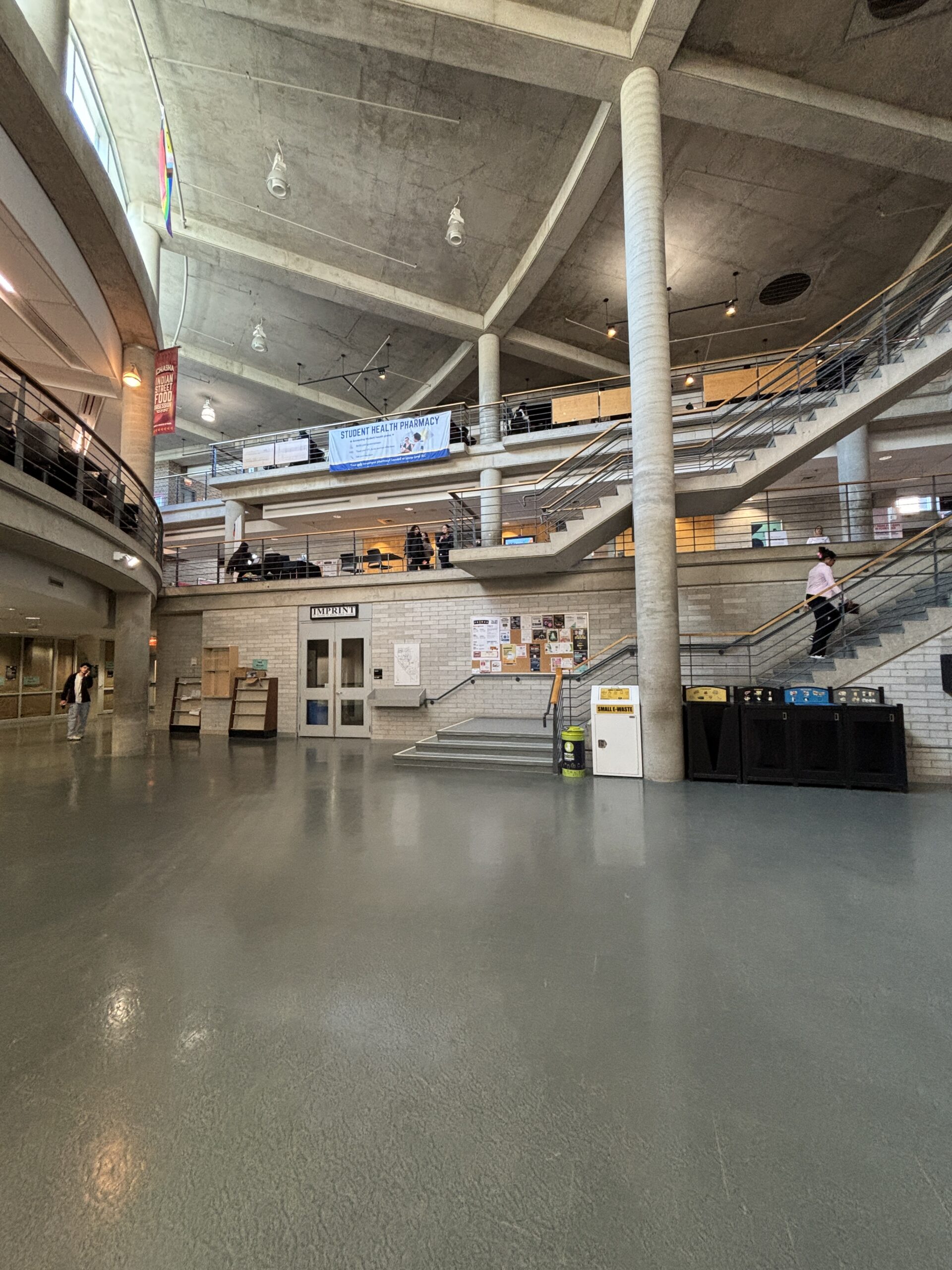 Wide shot of a multi-level, open atrium in a modern SLC building with stairs and people walking or sitting.