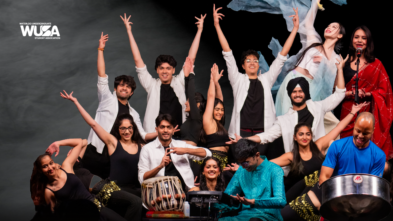 A diverse, cultural group of performers dancing and playing musical instruments on stage, smiling brightly.