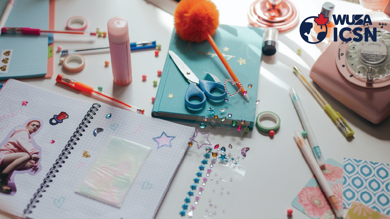 A desk with notebooks, stickers, scissors, pens, and crafting supplies scattered around—perfect for planning your next After-Hours Social.