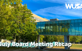 Sunny campus with glass walkway, trees, and text "July Board Meeting Recap" and "WUSA" in the corner, capturing the highlights of the recent July Board Meeting.