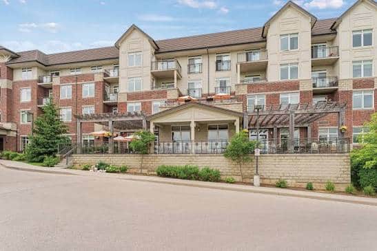 Four-story brick apartment building with balconies, large windows, and a covered patio area in front, perfect for gatherings like those hosted by UW GlamourGals at Chartwell Clair Hills Retirement Home.