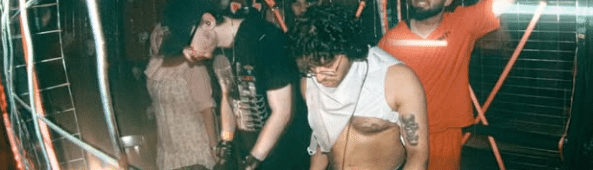 People DJing rave music at a party in a dimly lit, enclosed space known as the gRAVEyard.
